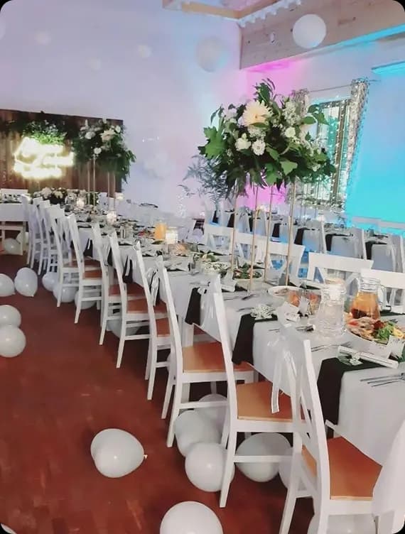 sala z dwoma dużymi stołami, białe balony, elegancka zastawa, biały obrus