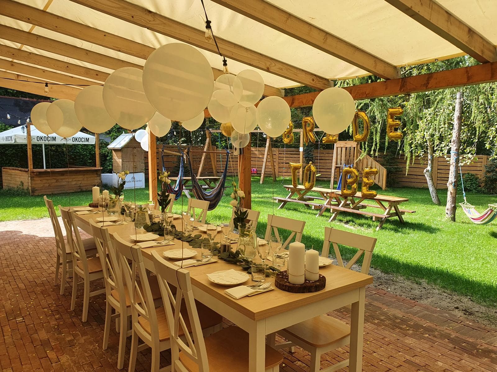 biały stół na zewnątrz, nad nim wiata i balony