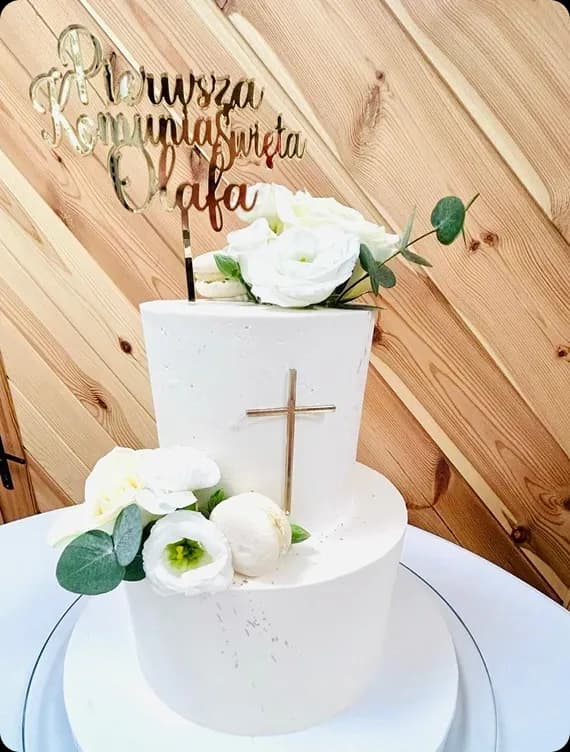 biały tort ze złotym krzyżem, udekorowany białymi różami