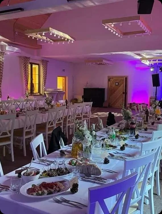 biały zastawiony stół biały obrus, w tle sala w kolorowych światłach